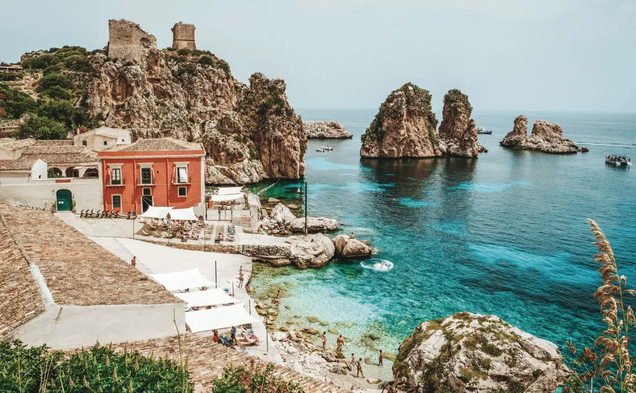 A picturesque cove with turquoise waters, rocky islets, and a charming village, this is a must-see among top places to visit in Sicily.