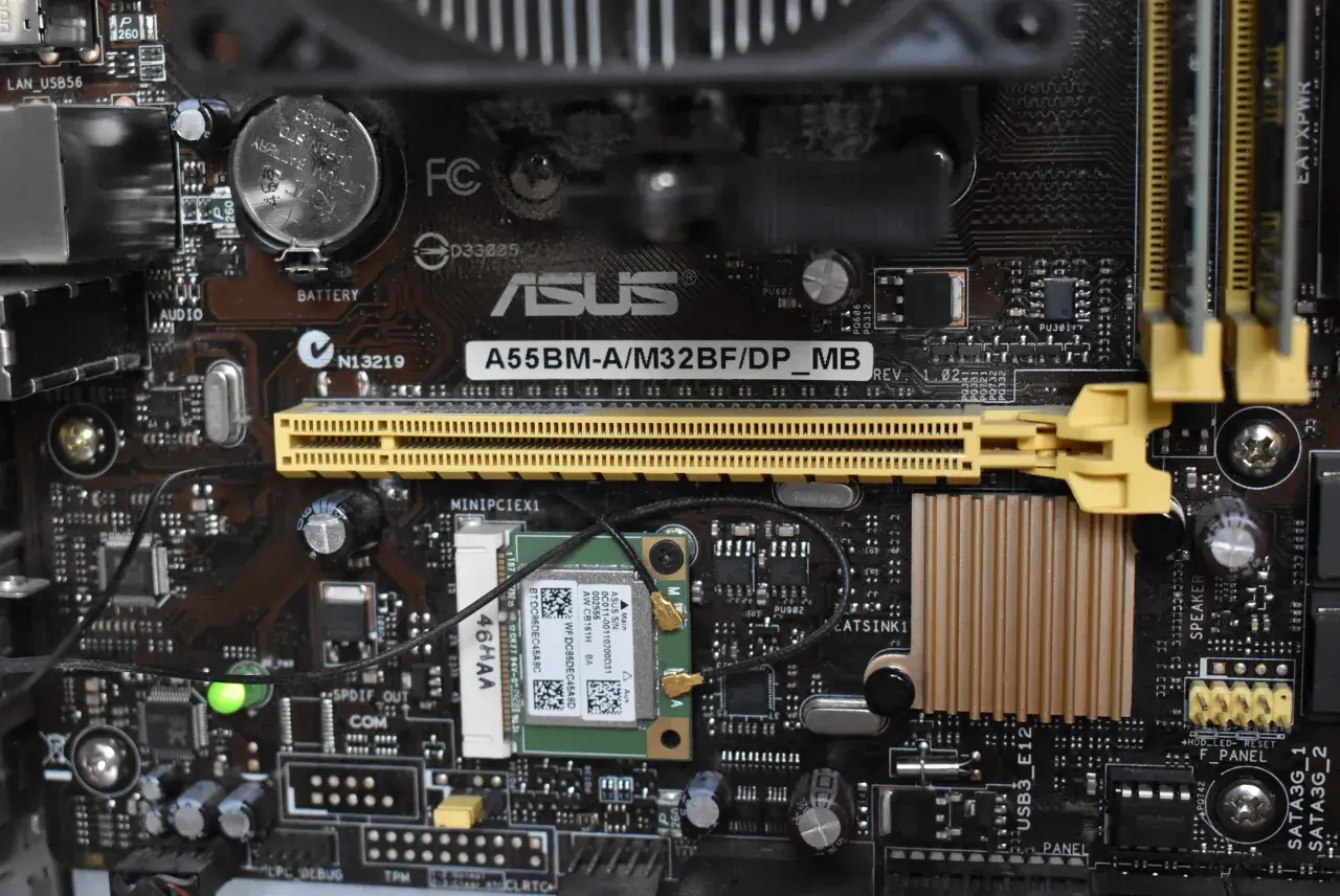 Carte mère ASUS A55BM-A/M32BF/DP_MB avec branchement carte mère visible, incluant une carte Wi-Fi et des connecteurs.