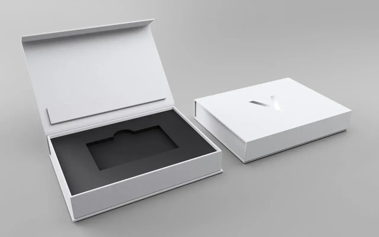 Elegante weiße Geschenkbox mit schwarzem Inlay, ideal für Karten verpacken Ideen. Ein silbernes Logo ziert den Deckel.