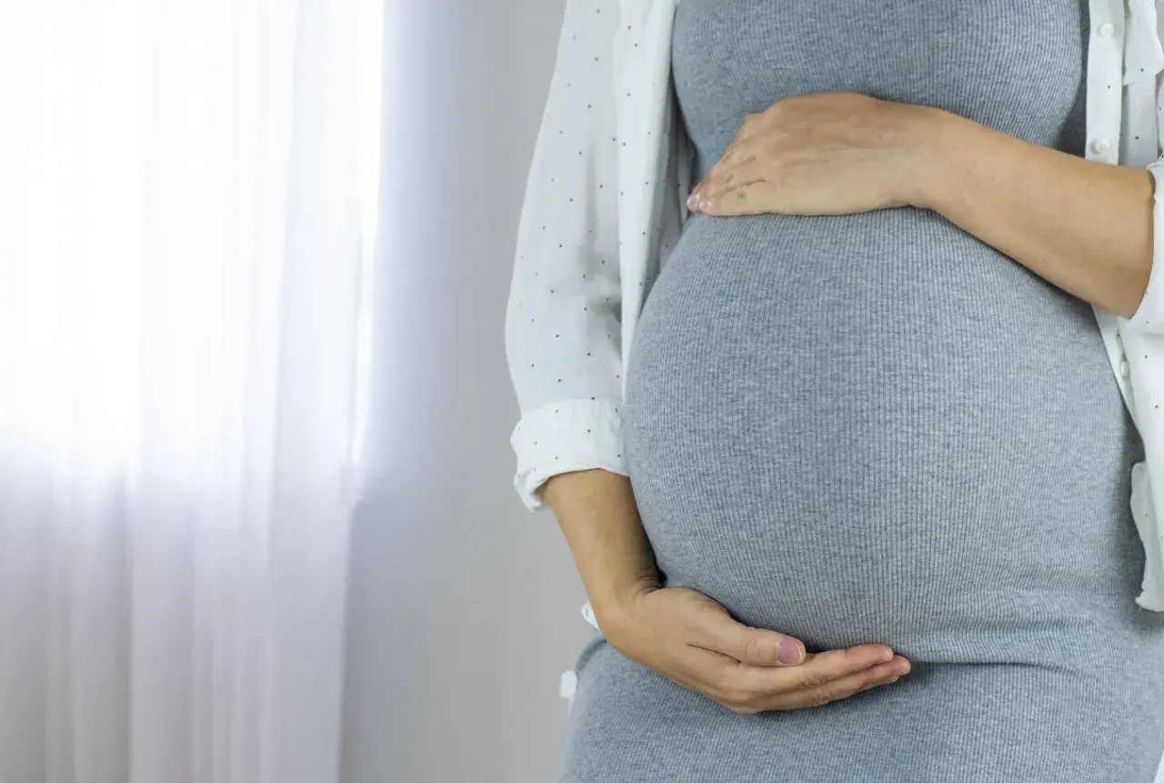 Kobieta w ciąży z dłońmi na brzuchu. Może to być związane z cholestazą ciążową.