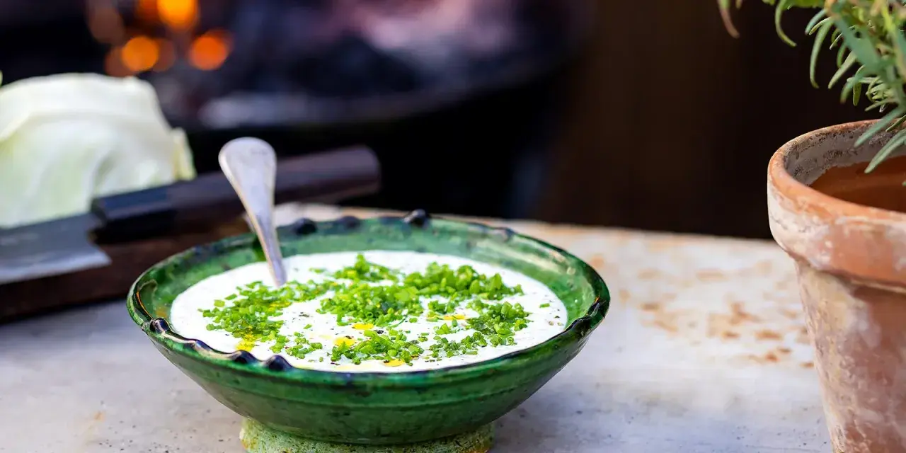 Grönskande skål med krämig ranch dressing, toppad med färska örter. En sked vilar i skålen, redo att servera.