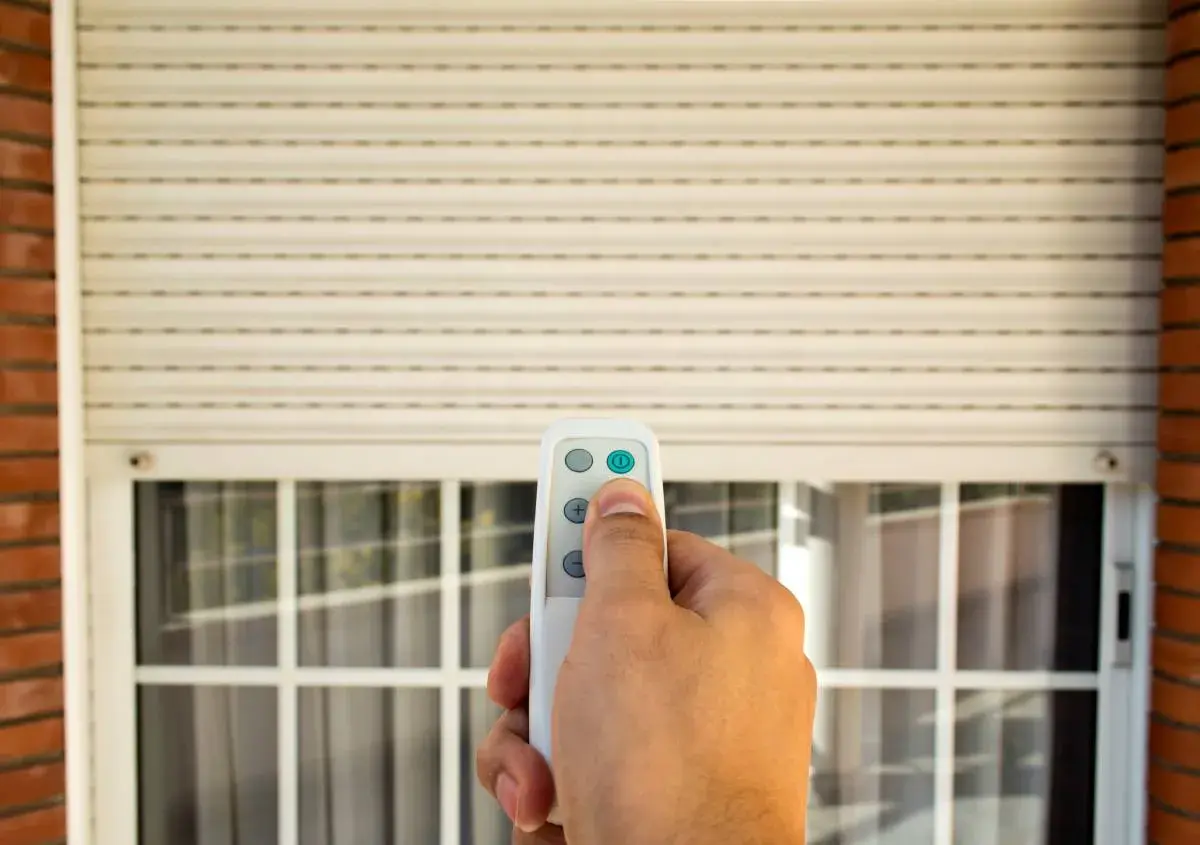 Mano che usa un telecomando per alzare una tapparella elettrica. Utile per capire quanto costa mettere le tapparelle elettriche.