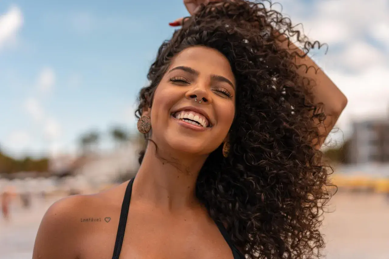 Donna sorridente con capelli ricci e fluenti, un esempio di come trattare i capelli ricci per un look naturale e radioso.