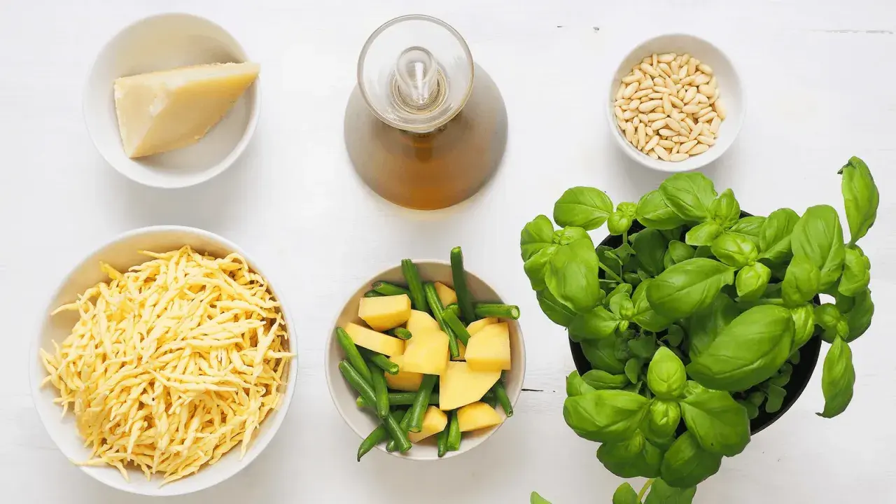 Ingredienti per un pesto senza pinoli: basilico fresco, formaggio grattugiato, patate, fagiolini, olio e aglio.