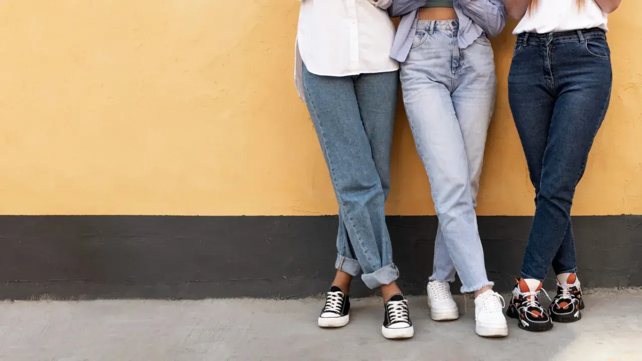 Trzy dziewczyny w szerokich jeansach i modnych sneakersach. Idealne inspiracje, jakie buty do szerokich spodni jeansowych.