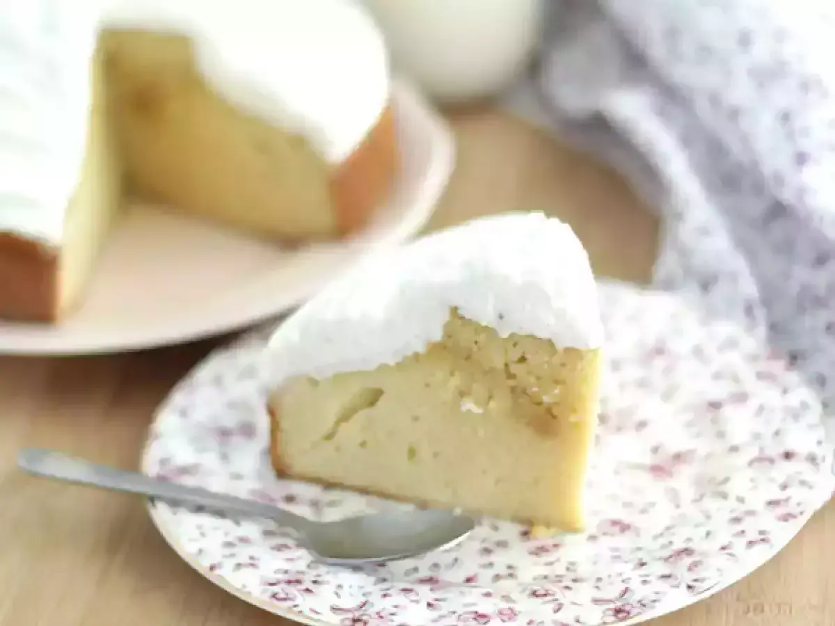 En saftig bit tres leches-kaka med fluffig vit topping, serverad på en blommig tallrik med en sked.