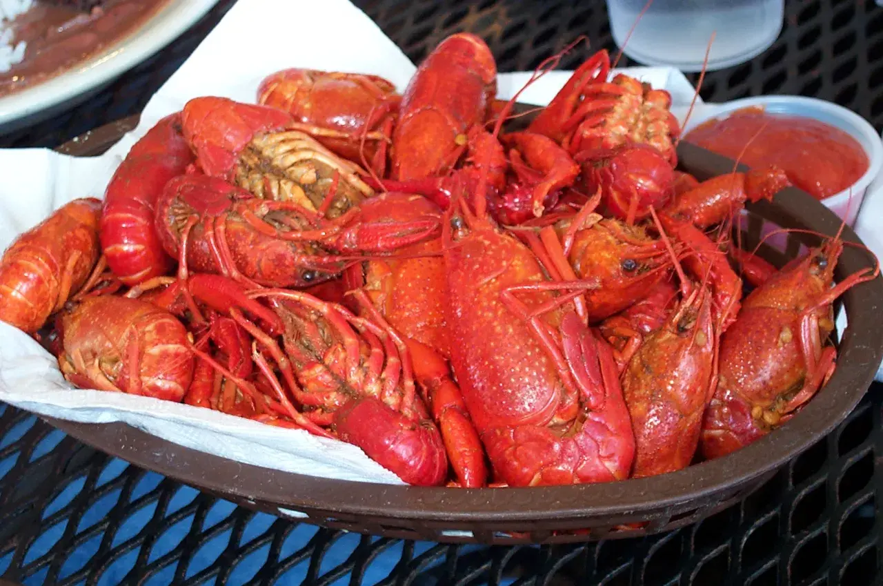 En korg full med saftiga kräftor, redo för en härlig seafood boil. En liten skål med röd sås står bredvid.