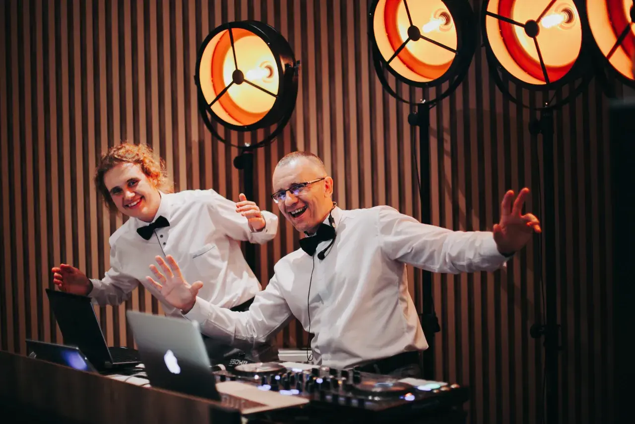 Dwóch DJ-ów w białych koszulach i czarnych muszkach, gotowych do zabawy. Zastanawiasz się, ile kosztuje dj na wesele?