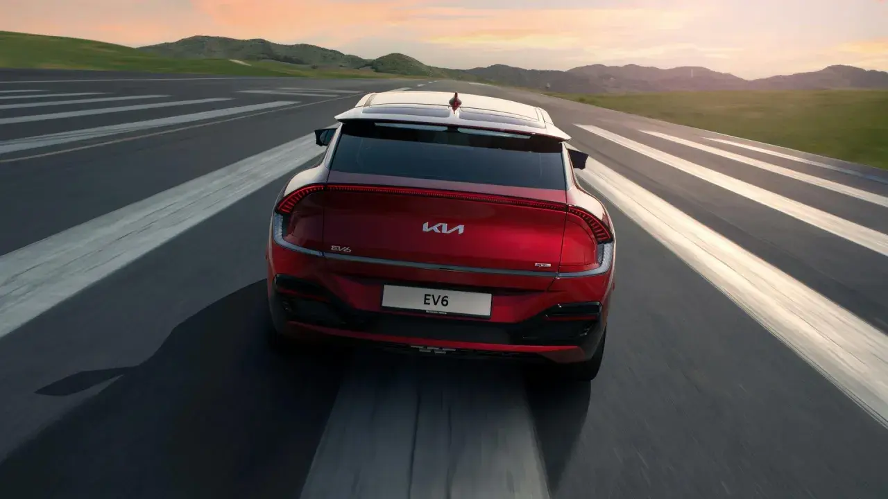 Röd Kia EV6 kör på en väg med vita linjer. En besiktning av spindelleder kan vara aktuell om det finns glapp.
