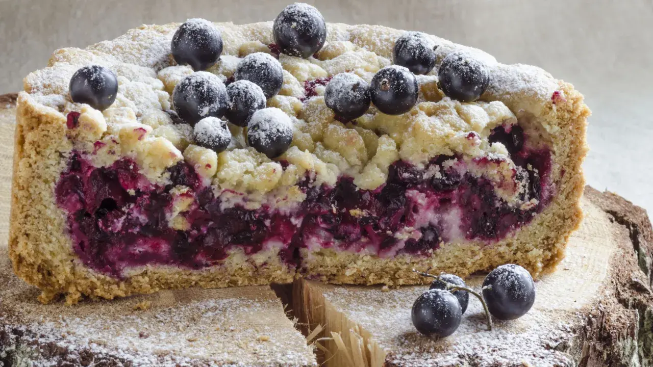 Saftiger Heidelbeerkuchen Landfrauenart mit Streuseln und frischen Beeren, bestäubt mit Puderzucker.