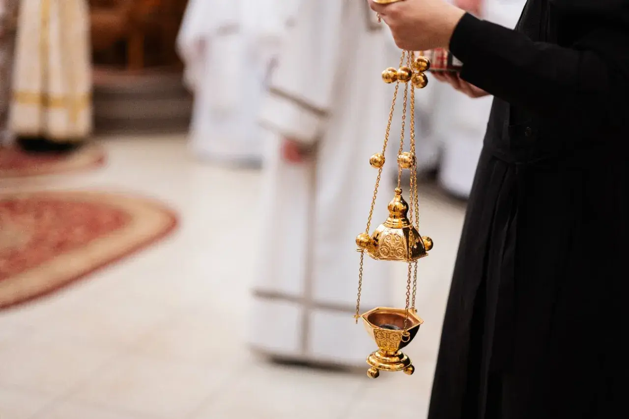 Złota kadzielnica w ręku osoby w czarnej szacie. Czy msza w środę popielcową jest obowiązkowa?
