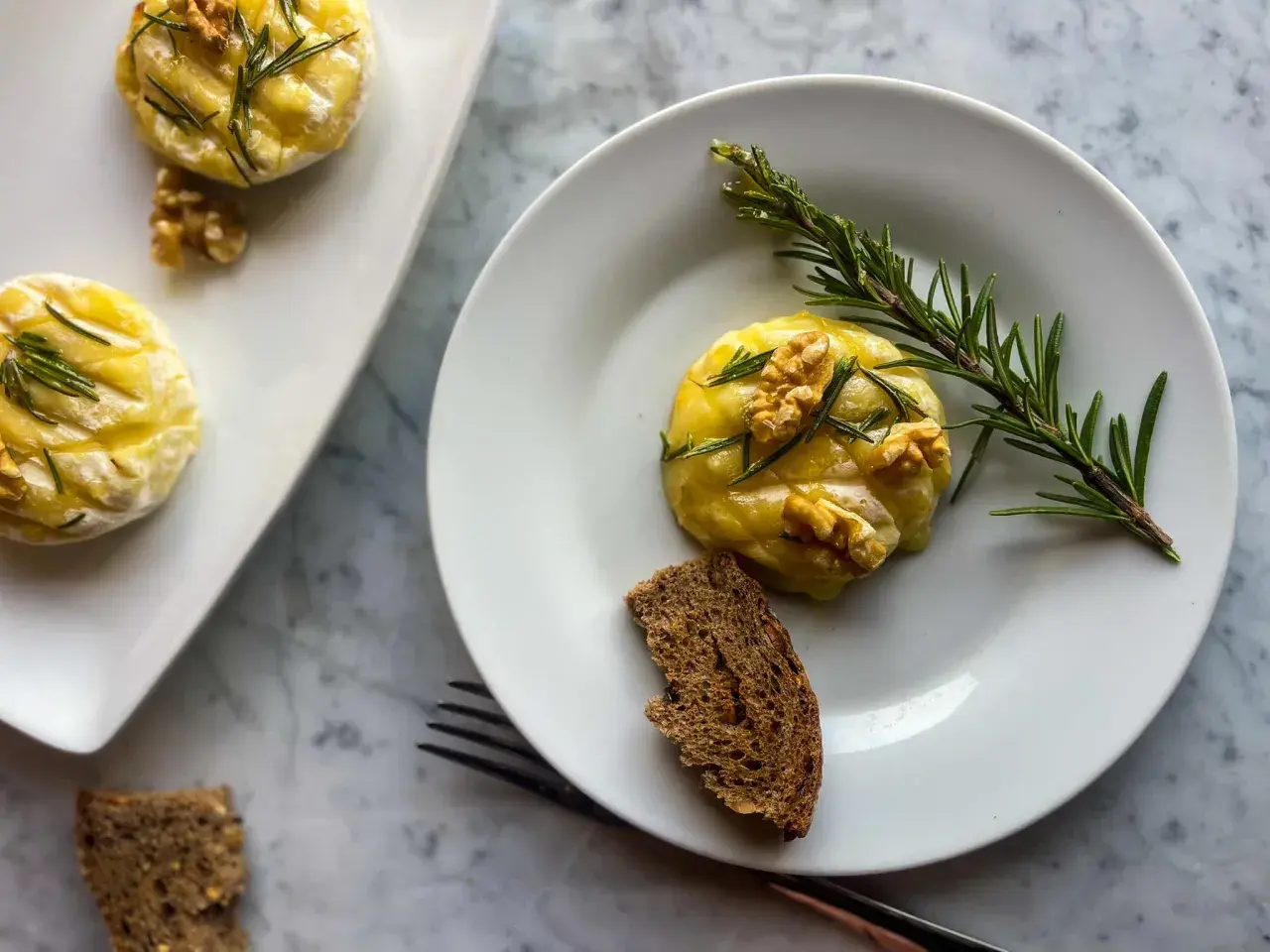 Deliziosi tomini in friggitrice ad aria, guarniti con noci e rosmarino, serviti con pane integrale.