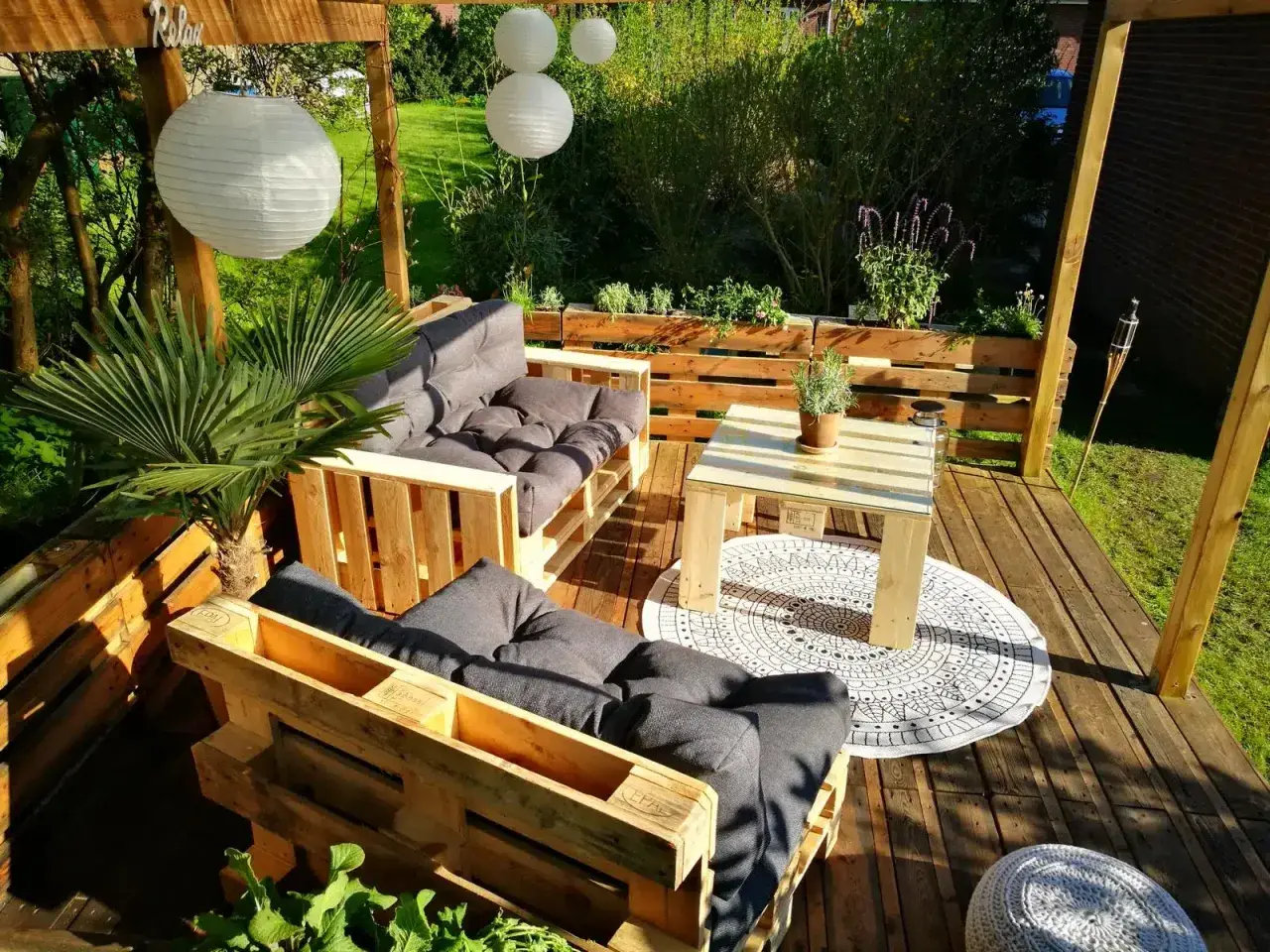 Gemütliche Lounge-Ecke mit Palettenmöbeln. Tolle Paletten Ideen für den Garten, mit Sitzbank, Tisch und Pflanzen.
