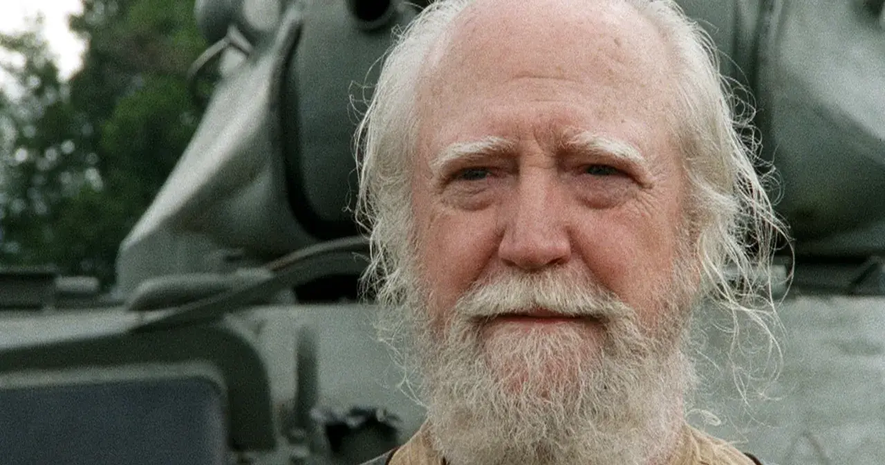Hershel Greene, członek obsady "Żywych trupów", z siwą brodą i włosami, na tle pojazdu.