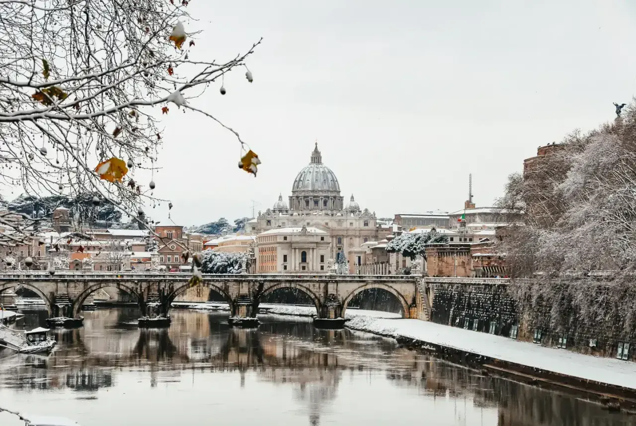 Un raro freddo a Roma imbianca il Tevere e i ponti, con San Pietro sullo sfondo.