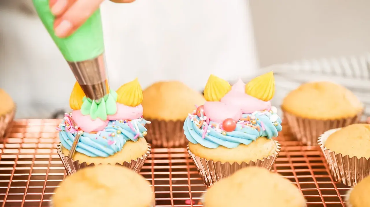 Decorazione di cupcake con crema al burro colorata, zuccherini e perline.