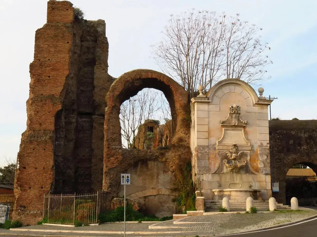 Antica porta furba metro, con fontana e rovine romane.