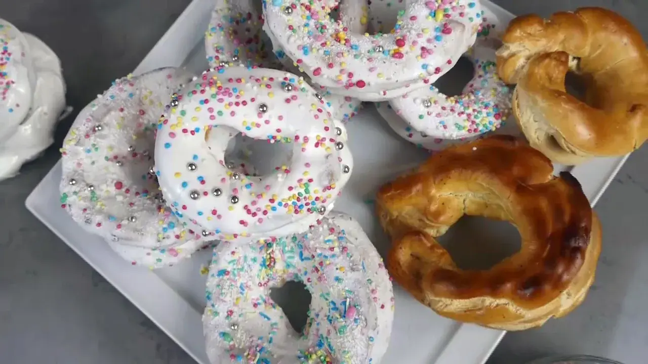 Biscotti a ciambella con glassa bianca e zuccherini colorati, pronti per essere gustati. La glassa per biscotti che si asciuga subito li rende perfetti.