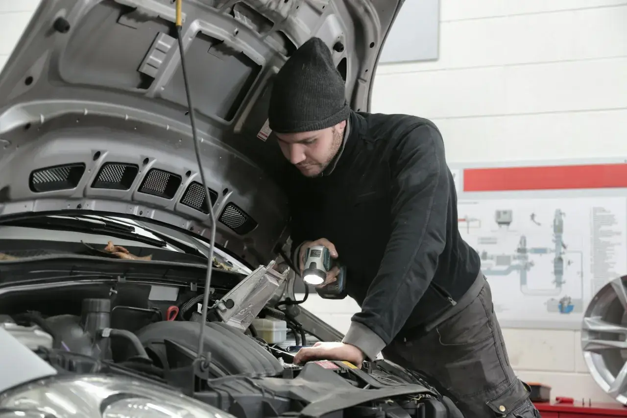 Mechanik z latarką bada silnik 1.9 TDI.