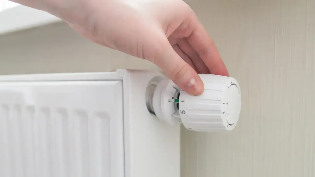 Mano ajustando el termostato de un radiador para decidir a que temperatura poner los radiadores y ahorrar energía.
