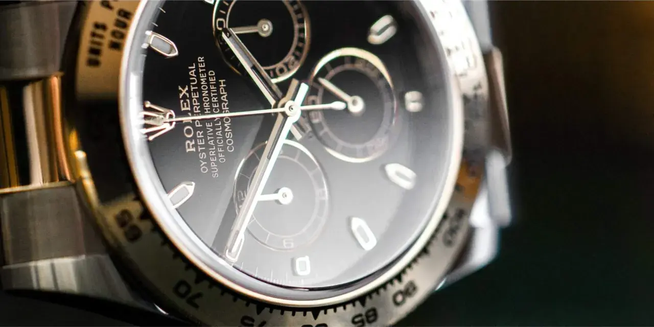 Primer plano de un Rolex Daytona con esfera negra y cristal hesalite. Los detalles del cronógrafo y la inscripción son visibles.