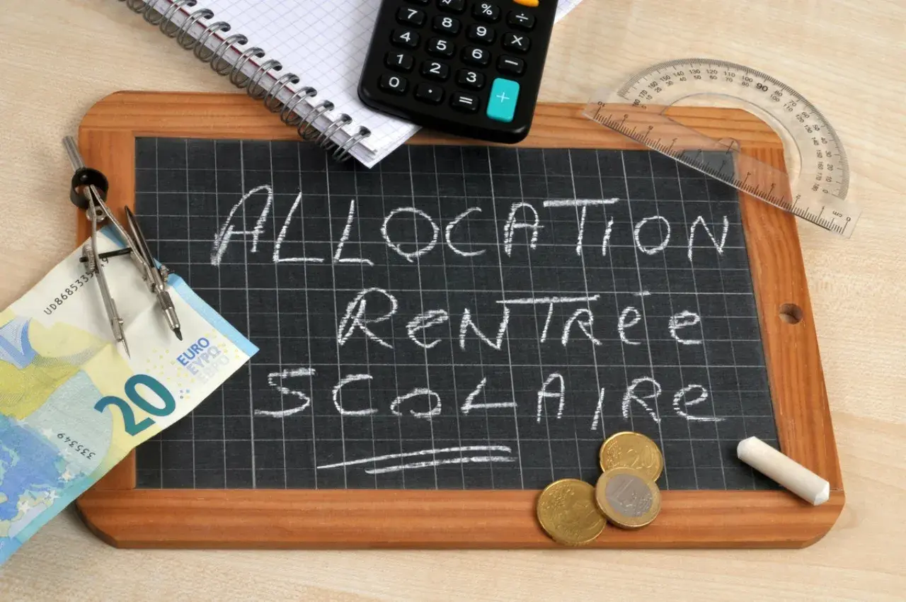 Tableau noir avec "Allocation Rentrée Scolaire" écrit à la craie. Un billet de 20 euros, des pièces, une calculatrice et un compas suggèrent un dépassement de plafond budgétaire.