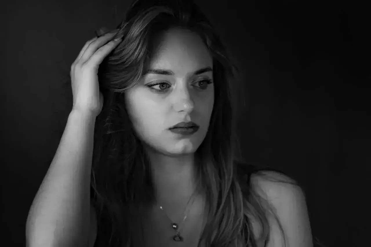 Kobieta z dłonią we włosach, w nastrojowym, low key fotografii.