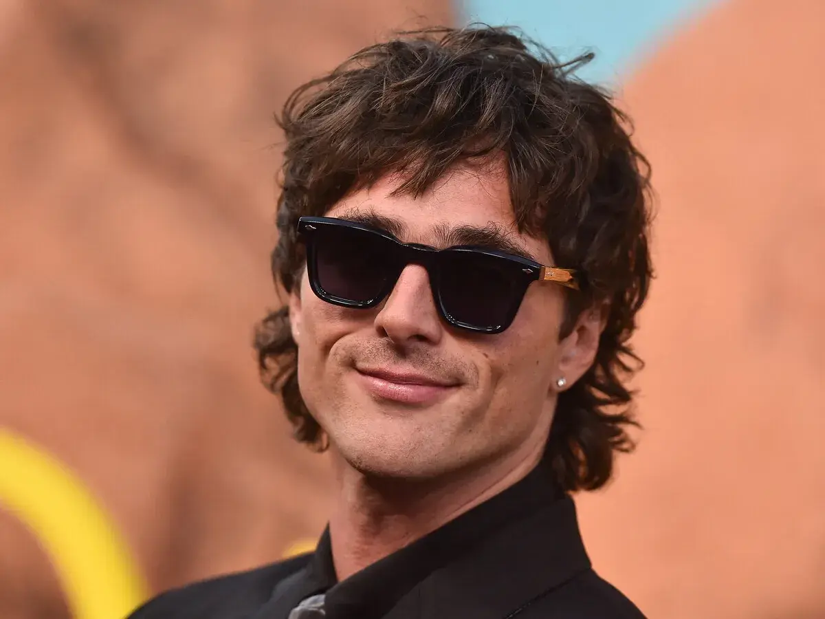 Hombre con corte de pelo moderno, gafas de sol oscuras y sonrisa. Un estilo que anticipa el corte de pelo hombre 2026.
