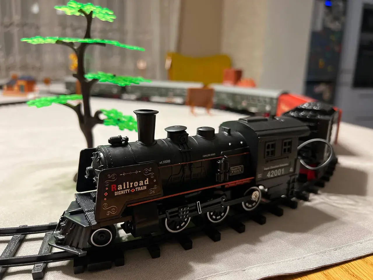 Czarny, zabytkowy silnik lokomotywy z napisem "Railroad Dignity Train" na torach, obok zielonego drzewka.