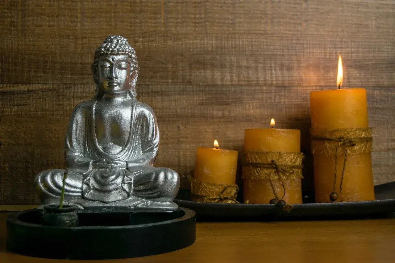 Srebrny Budda w medytacji, otoczony płonącymi świecami. Czy buddyści wierzą w reinkarnację? Ta scena sprzyja refleksji.