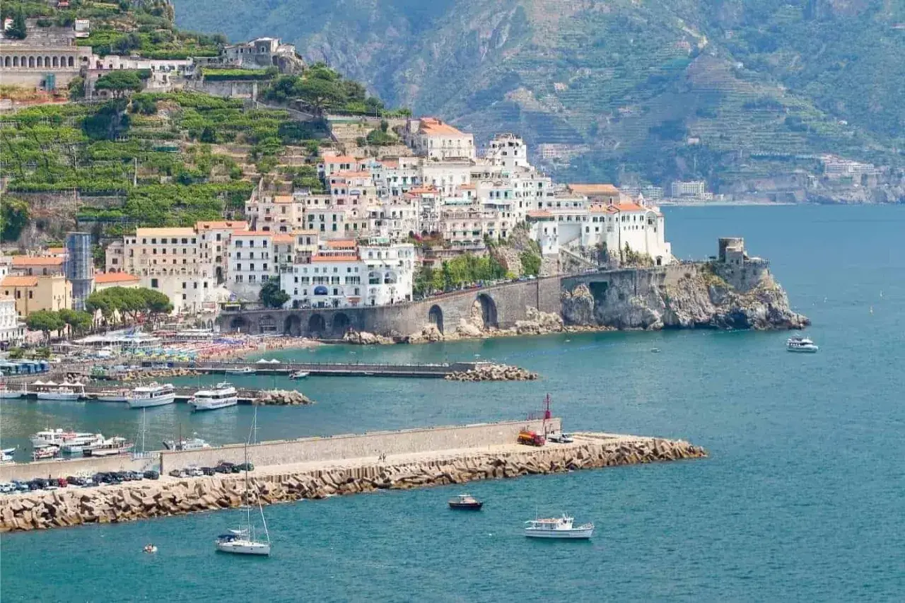 Amalfi: cosa vedere in un giorno. La pittoresca cittadina si affaccia sul mare blu, con case bianche aggrappate alla collina e un porto pieno di barche.