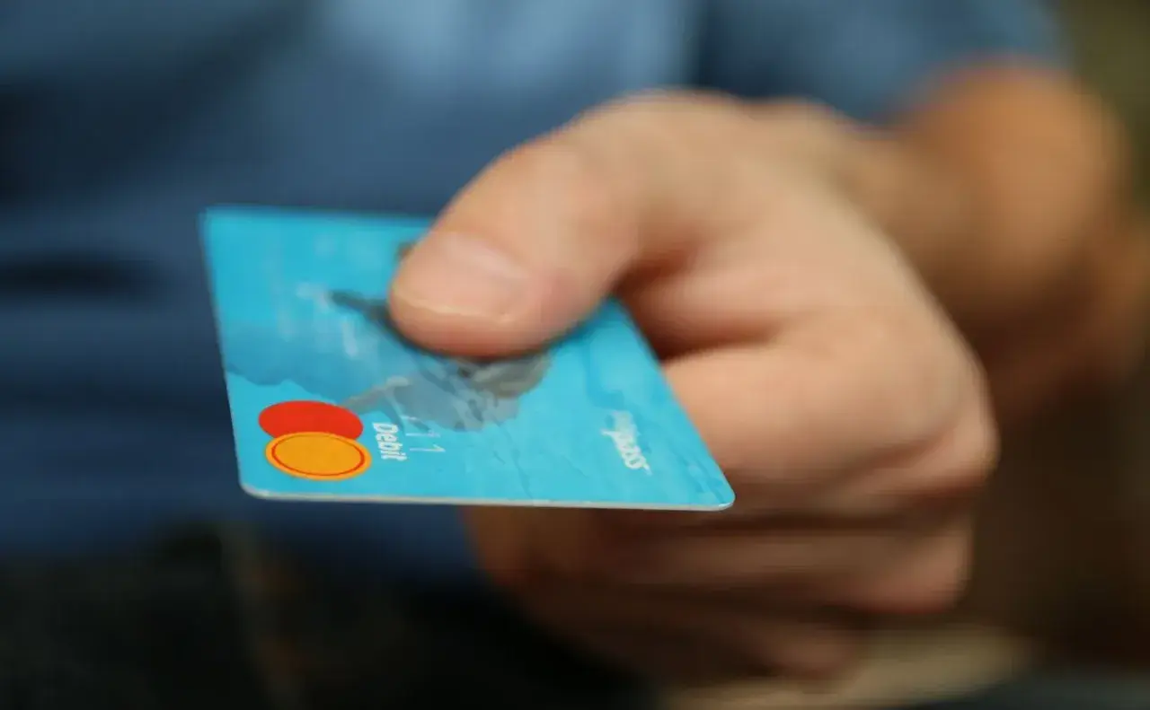 Main tenant une carte bancaire bleue, prêt à effectuer un achat. Il est possible de bloquer un paiement CB en cas de perte.