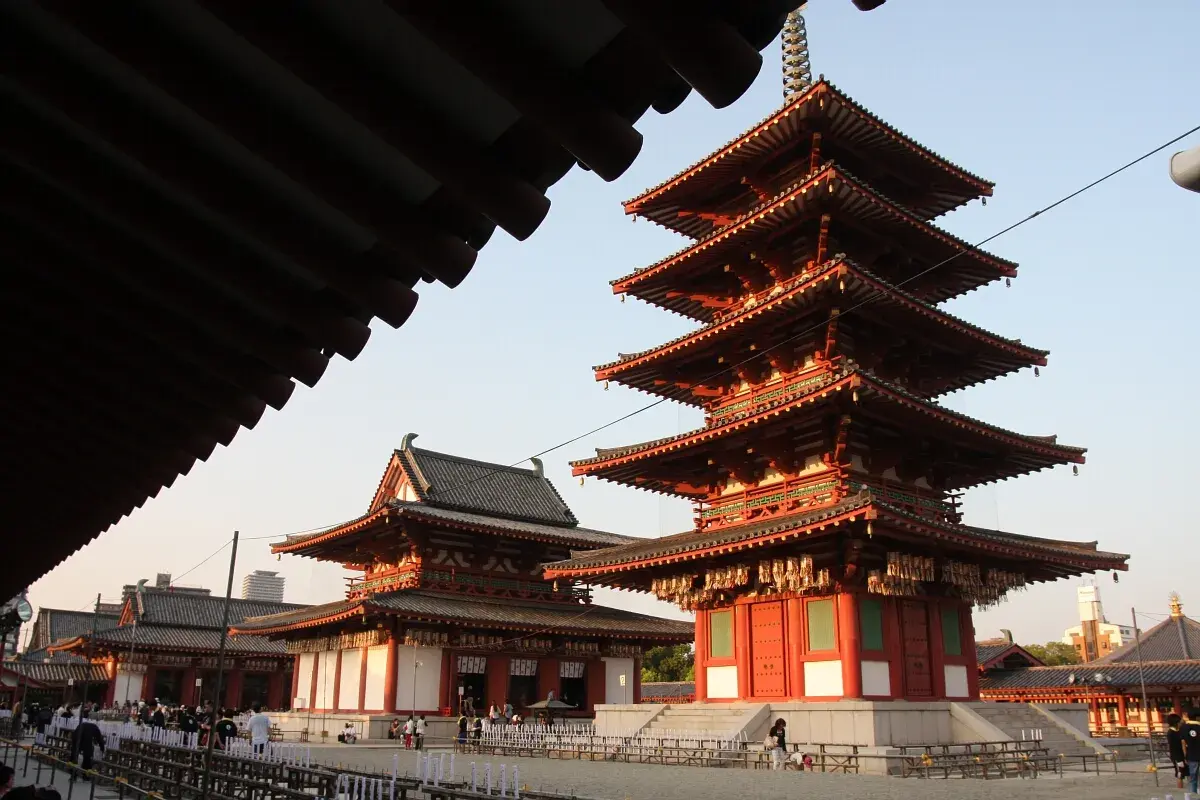 Pięciopiętrowa pagoda i inne budynki świątyni buddyjskiej w Japonii, z tradycyjnymi dachami i czerwonymi detalami.