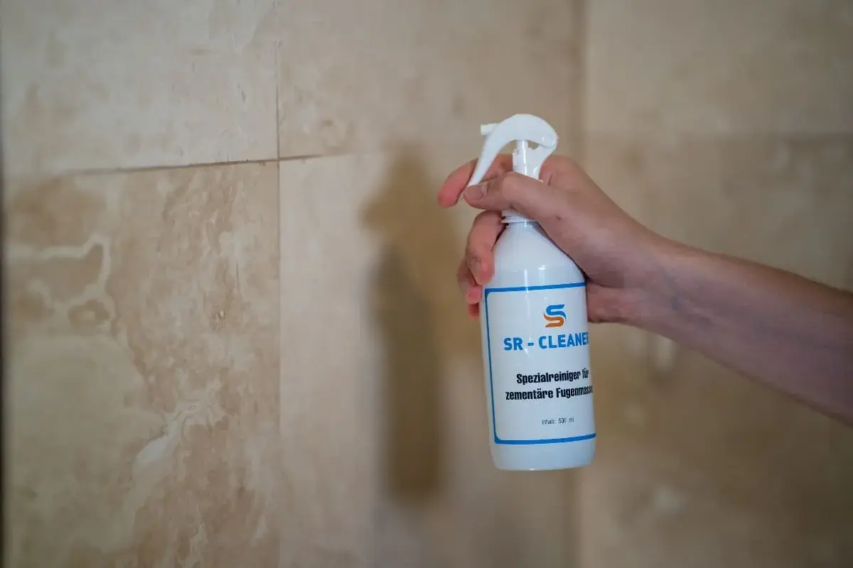 Hand hält SR-CLEANER Flasche, um **Fugen zu versiegeln** in der **Dusche**.