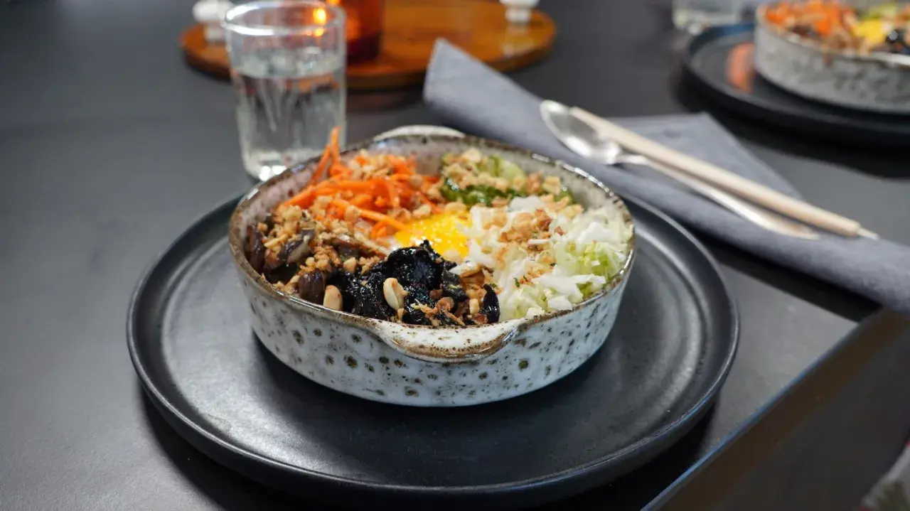 En vacker skål med bibimbap, fylld med ris, grönsaker, svamp och ett stekt ägg. Perfekt för ett snabbt och gott bibimbap recept.