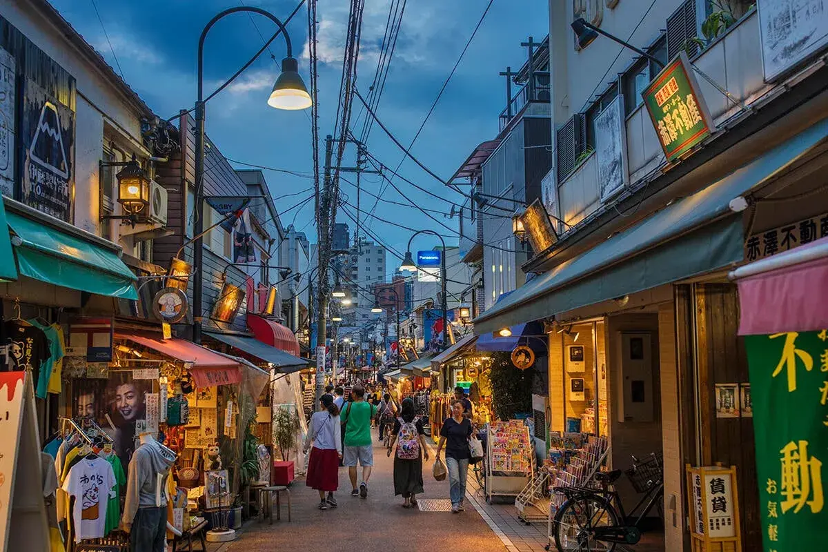 En livlig gata i gamla Tokyo med butiker, skyltar och människor som promenerar.