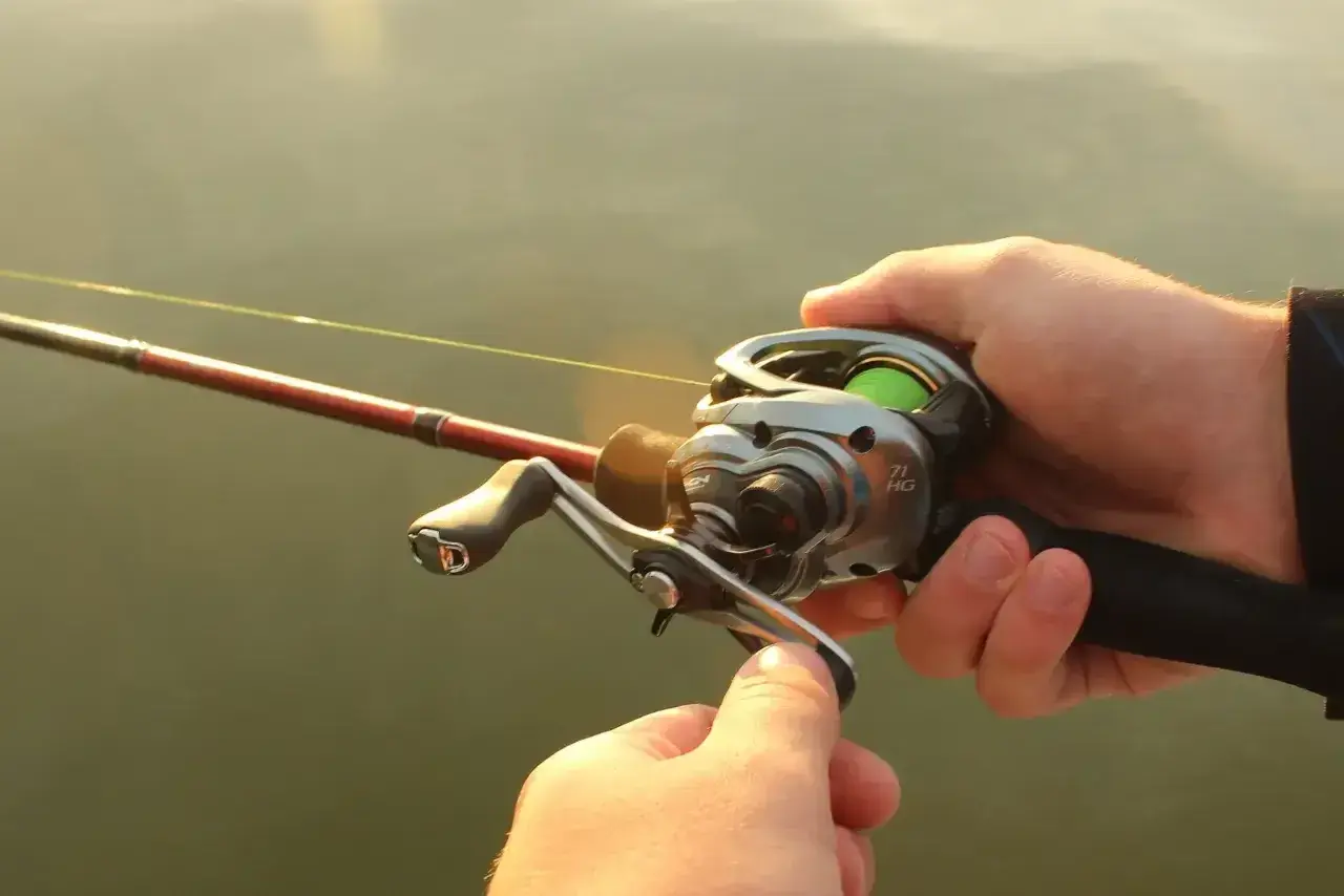 Dłonie trzymają wędkę z kołowrotkiem, gotowe do rzutu. Precyzyjne **casting spinning** to klucz do sukcesu.