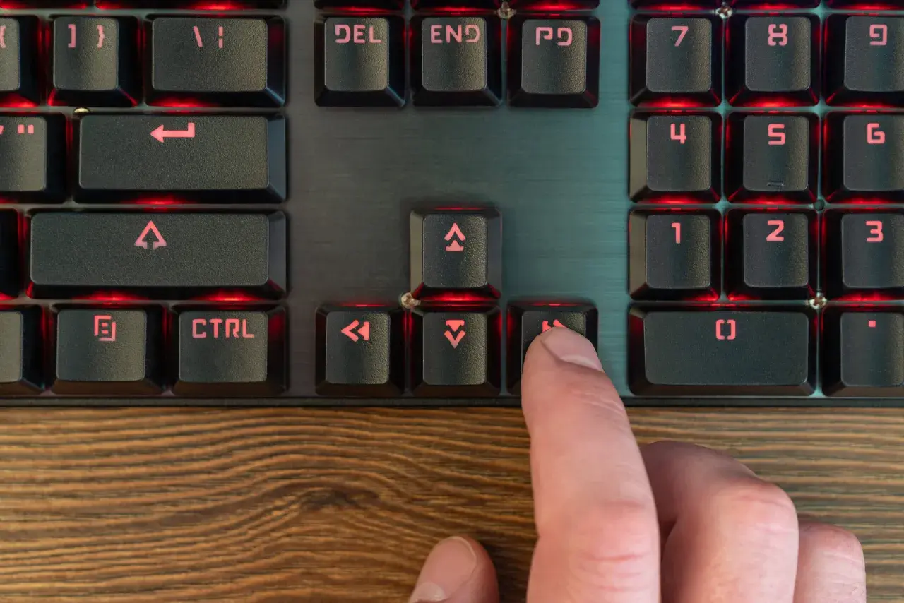 Palec naciska klawisz "Home" na podświetlanej klawiaturze programisty, co może być częścią skrótu klawiszowego.