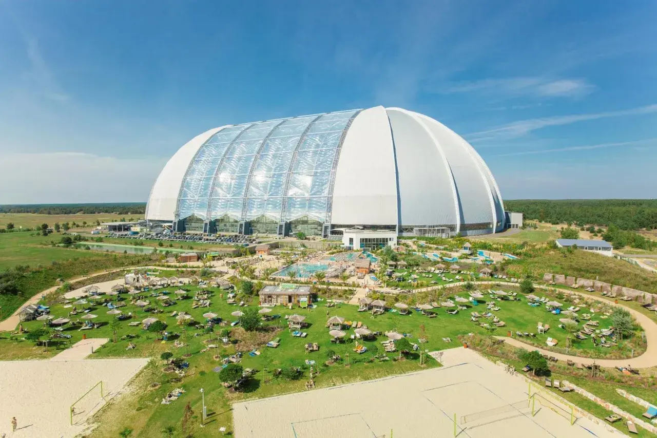 Krausnick tropical island: ogromna hala z basenami i leżakami na trawie, plaża do siatkówki, otoczona zielenią.