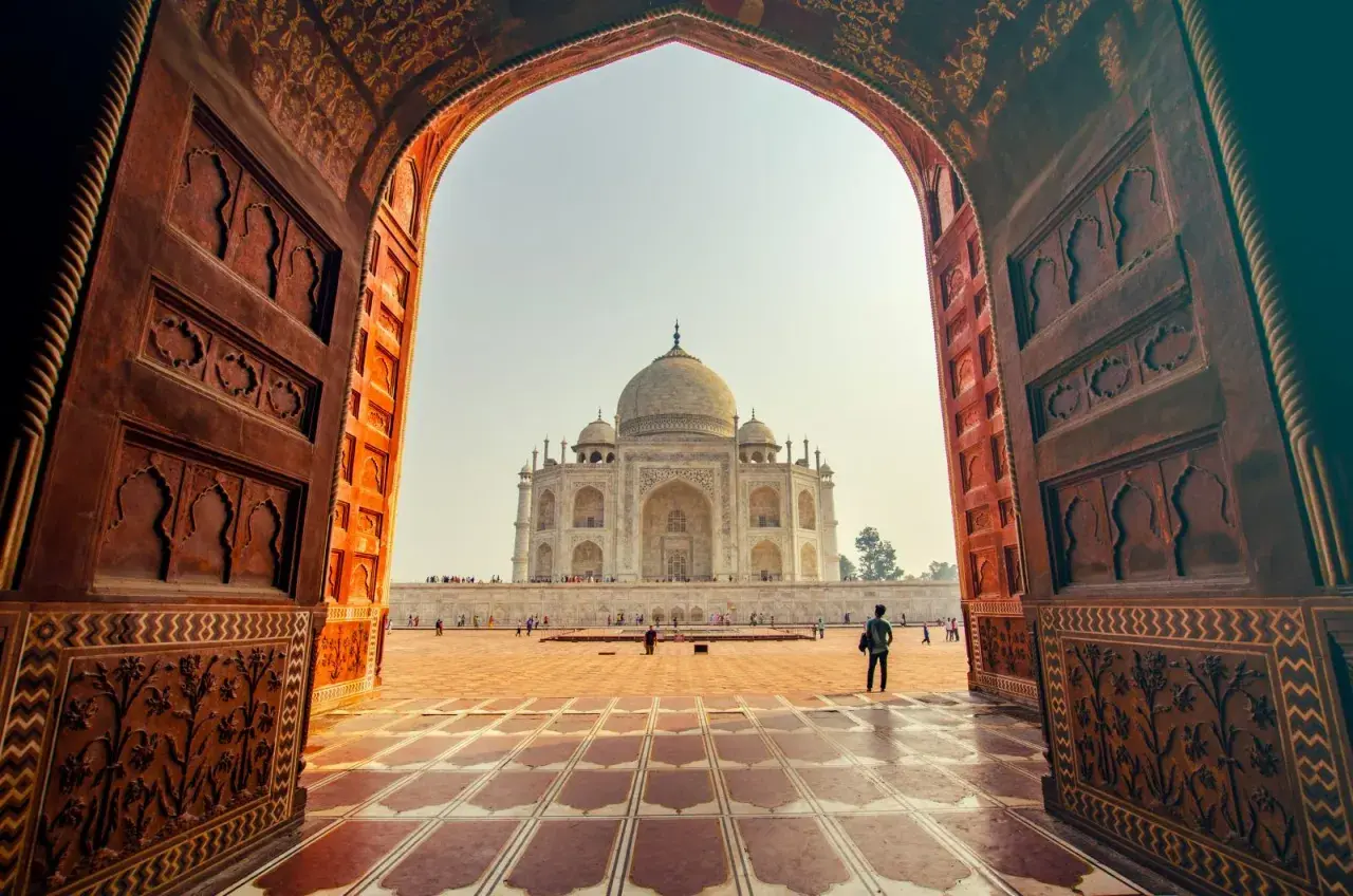 Widok na Taj Mahal przez zabytkowy łuk. Idealne miejsce na niezapomniane indie wakacje.
