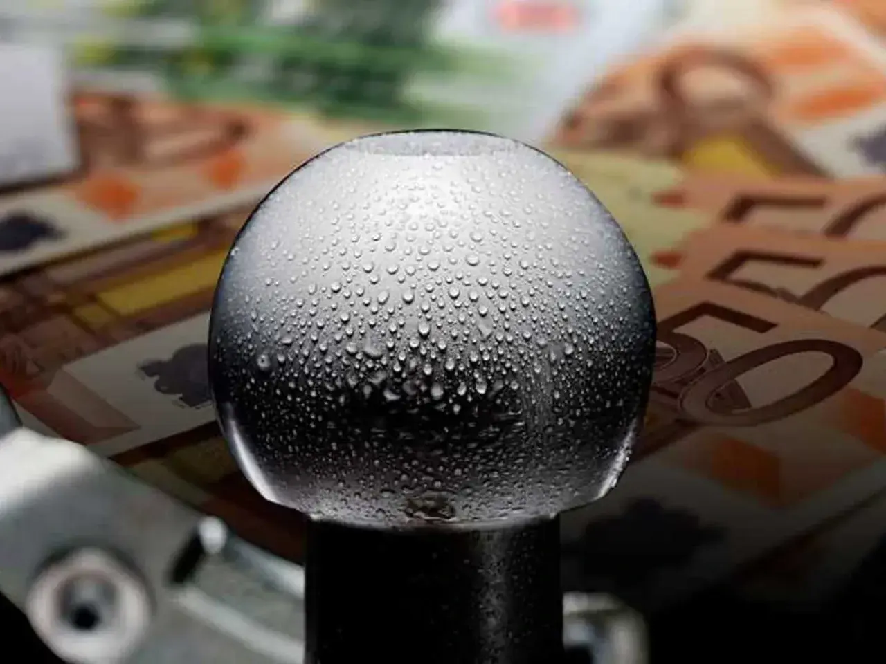Gocce d'acqua su un gancio traino, con banconote in euro sullo sfondo. Quanto costa omologare un gancio traino?