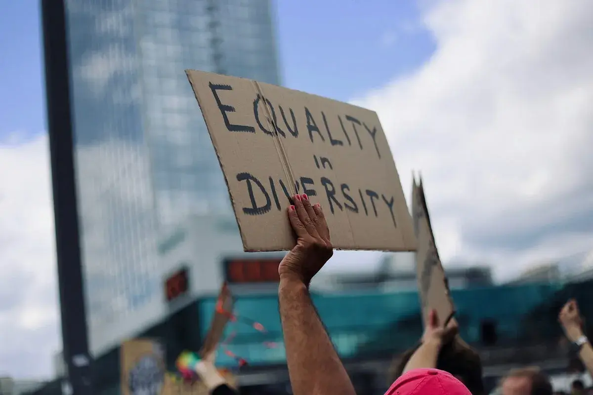 A hand holds a sign reading "EQUALITY in DIVERSITY," a powerful statement that inclusivity is a value.