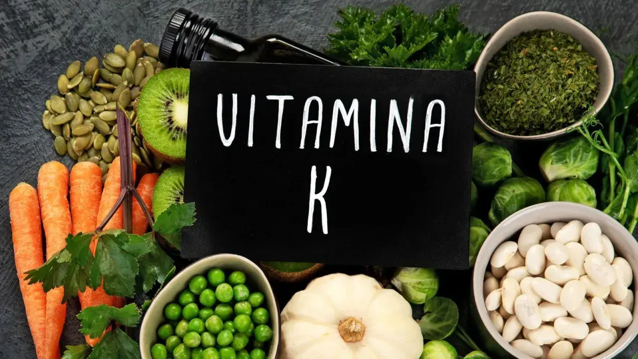 Variedad de alimentos ricos en vitamina K2: zanahorias, kiwi, semillas de calabaza, guisantes, coles de Bruselas, judías blancas y hierbas.
