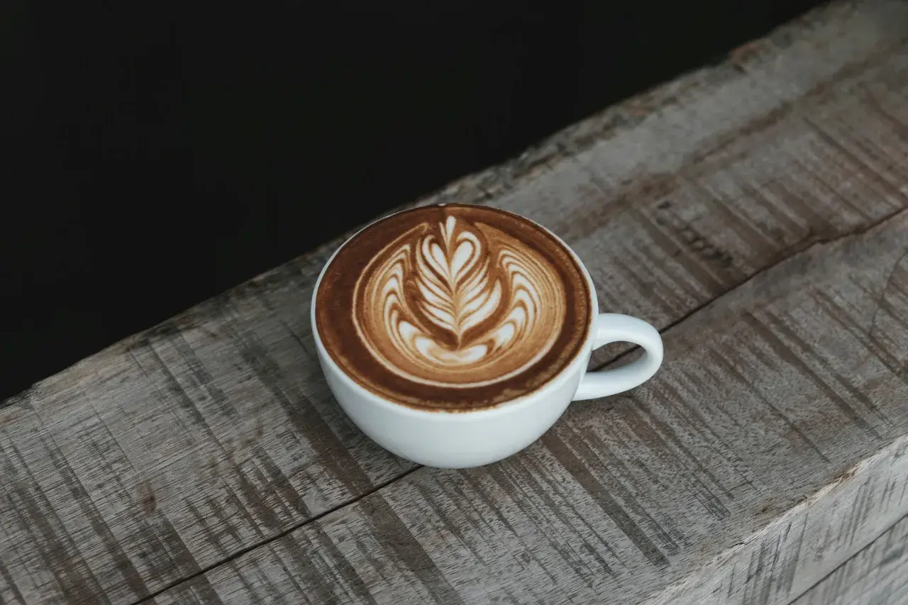 Eine Tasse Cappuccino mit Latte Art auf einem Holztisch. Die Menge des Kaffees ist perfekt für einen Genussmoment.