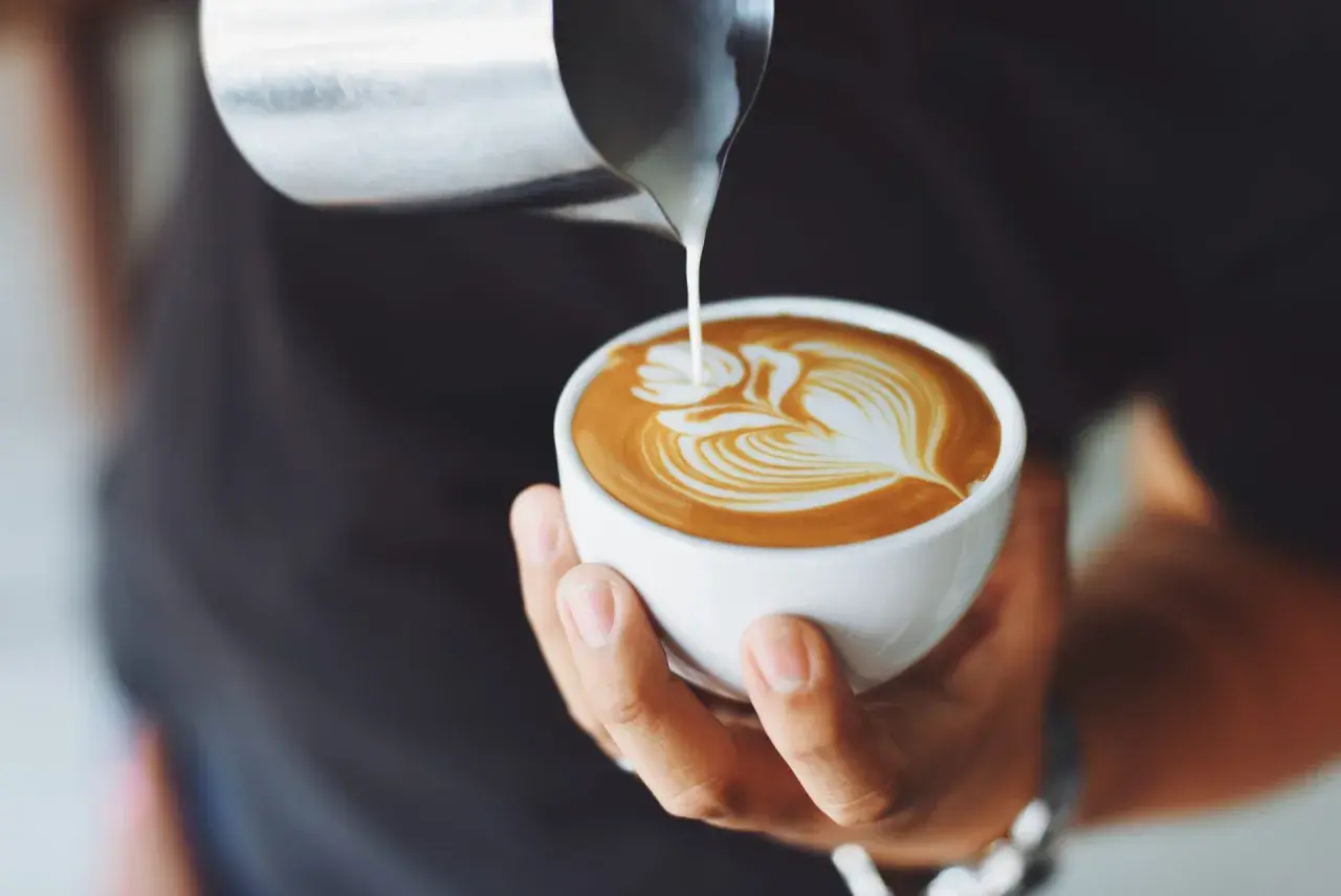 Barista tworzy latte art na kawie. Czy cappuccino ma kofeinę? Tak, zawiera ją espresso.