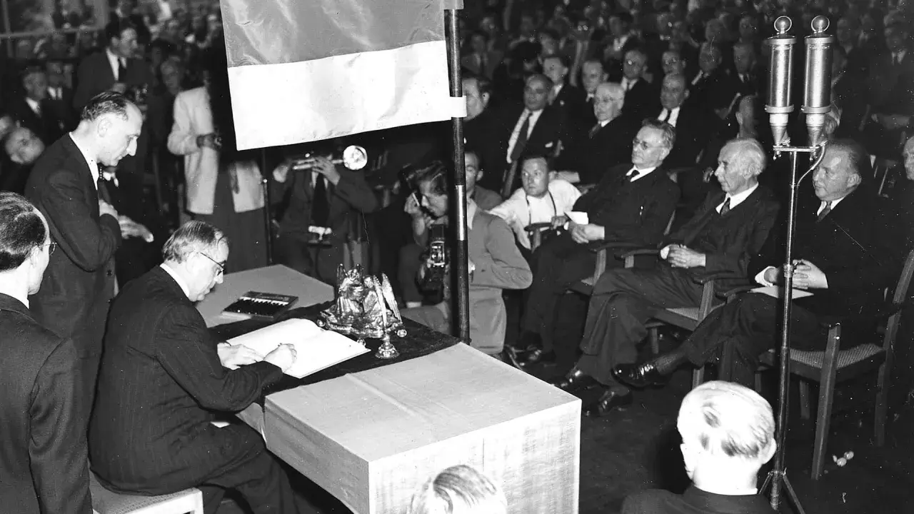 Männer in Anzügen versammeln sich, um die Unterzeichnung des Grundgesetzes zu beobachten. Wann wurde das Grundgesetz geschrieben? Am 23. Mai 1949.