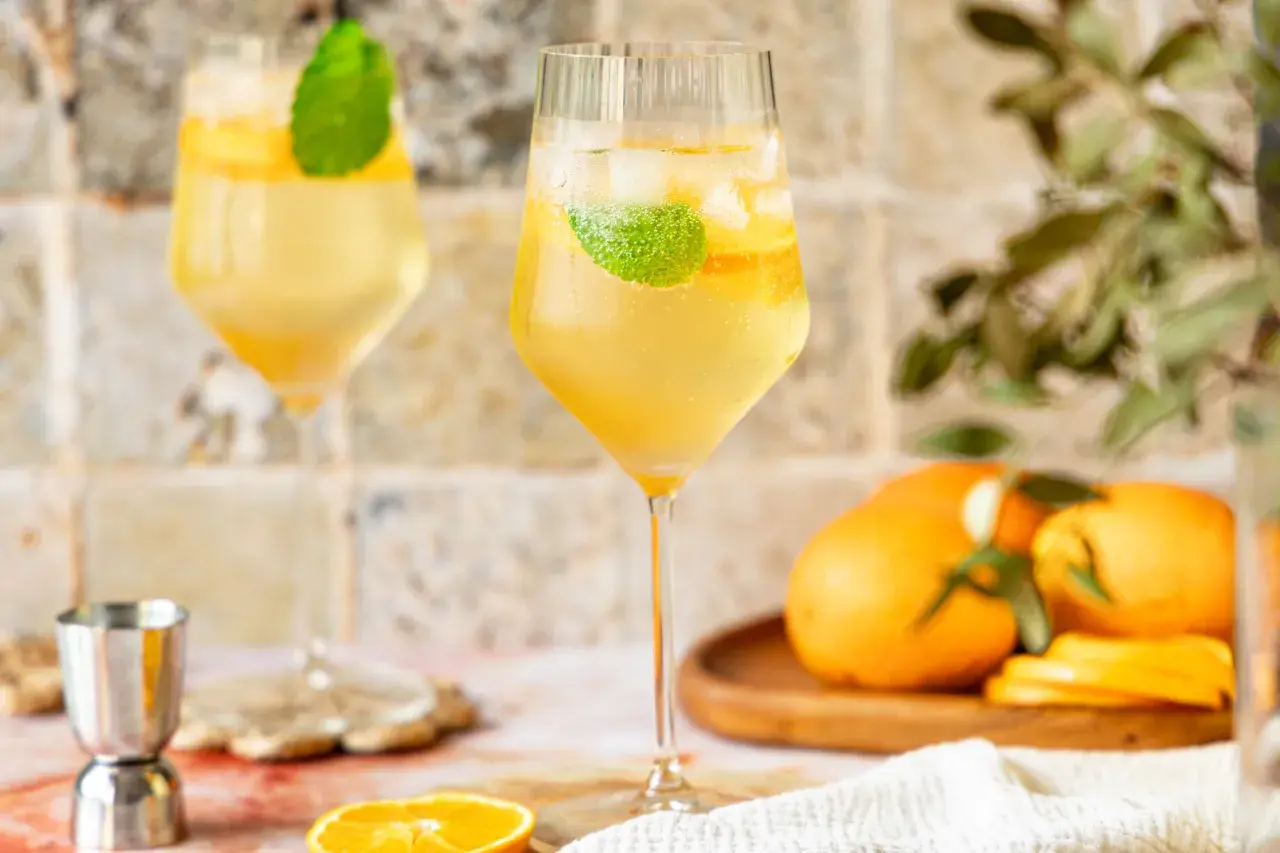 Erfrischender Lillet Spritz mit Eis, Minze und Orangenscheiben. Perfekt für einen sonnigen Nachmittag.