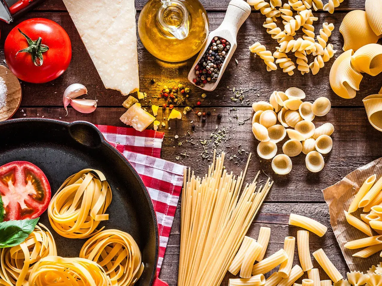 Verschiedene nudel arten, Tomaten, Parmesan, Olivenöl und Gewürze auf Holztisch.