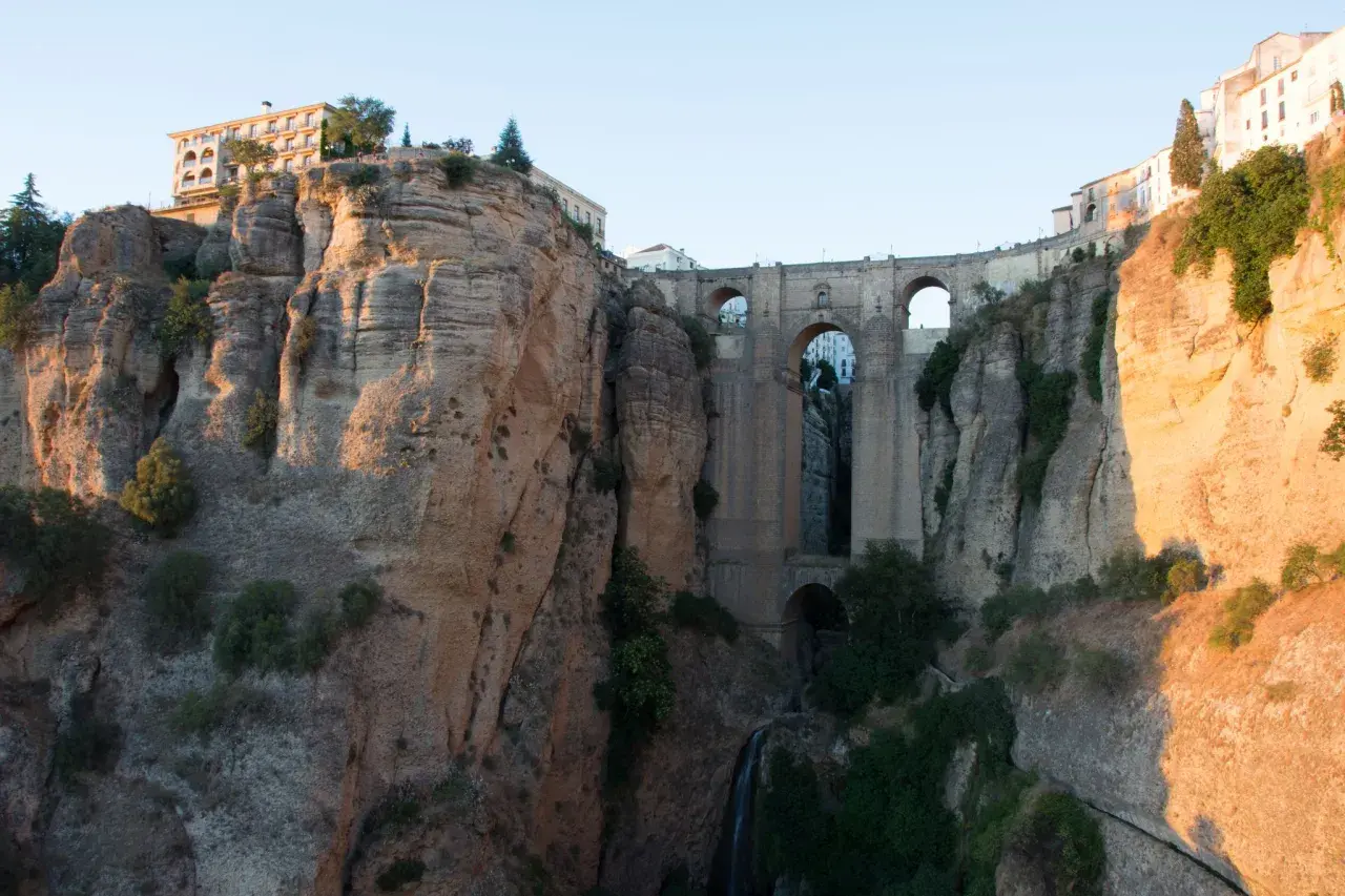 Impresionante puente de piedra sobre un profundo tajo, ideal para rutas por Ronda. Edificios se asoman al abismo.