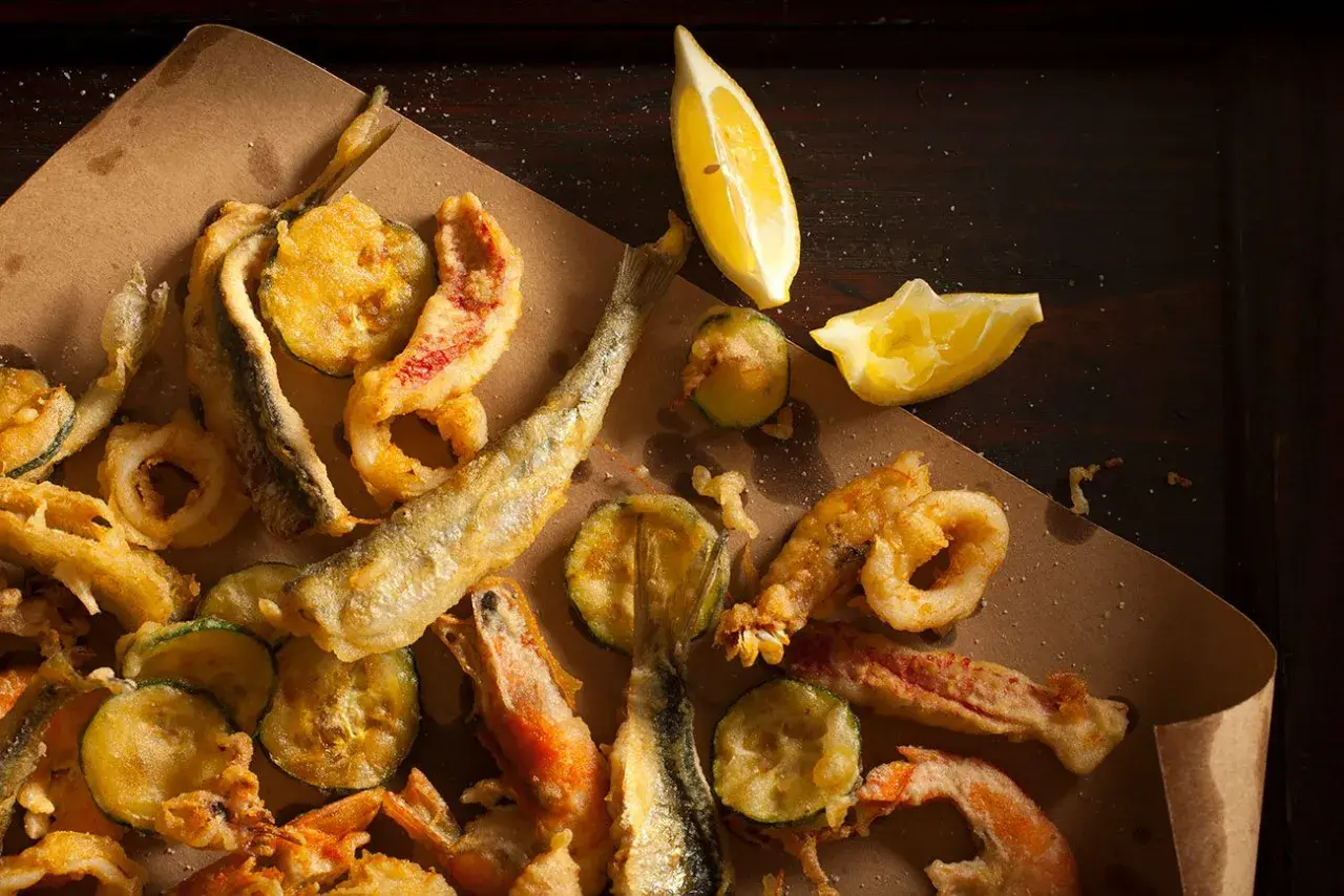 Fritto misto di mare e verdure, croccante e dorato, perfetto con il suo olio per frittura di pesce. Limone a spicchi per un tocco fresco.